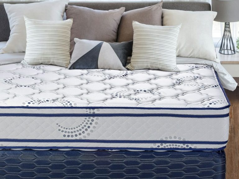 A neatly made bed with a patterned mattress and decorative pillows in a bright room.